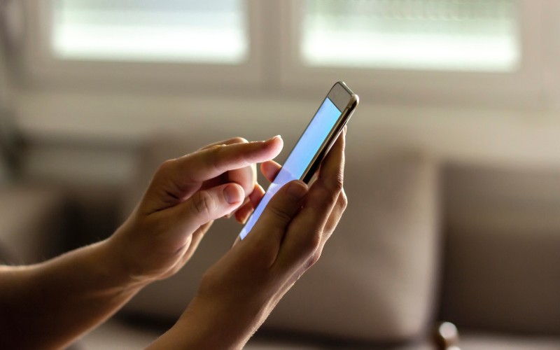 Duas mãos usando o celular para pesquisar a tabela de preço da amepla para estudantes
